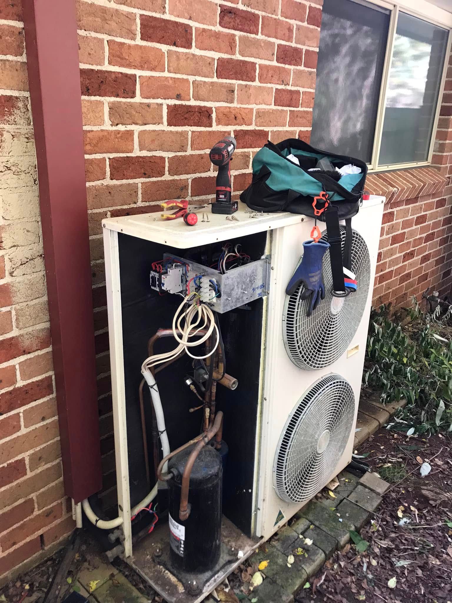 A HVAC Unit With Open Panel, Tools on Top, Near Brick Wall — Escarpment Air in Mount Saint Thomas, NSW