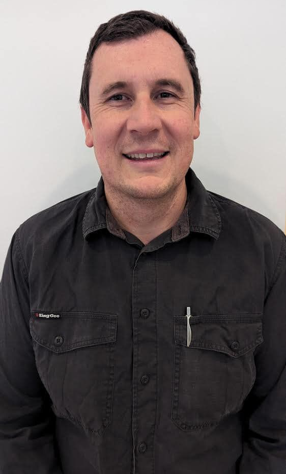 Man in a black button-down shirt smiling, standing against a plain white background. — Escarpment Air in Mount Saint Thomas, NSW