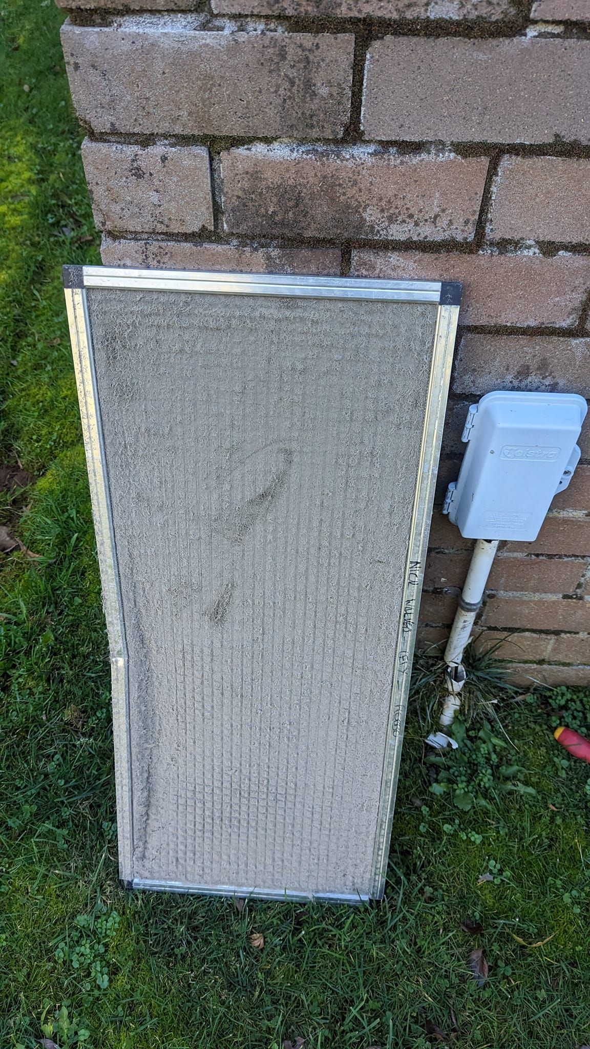 A Dirty, Rectangular Air Filter Leaning Against a Brick Wall — Escarpment Air in Mount Saint Thomas, NSW