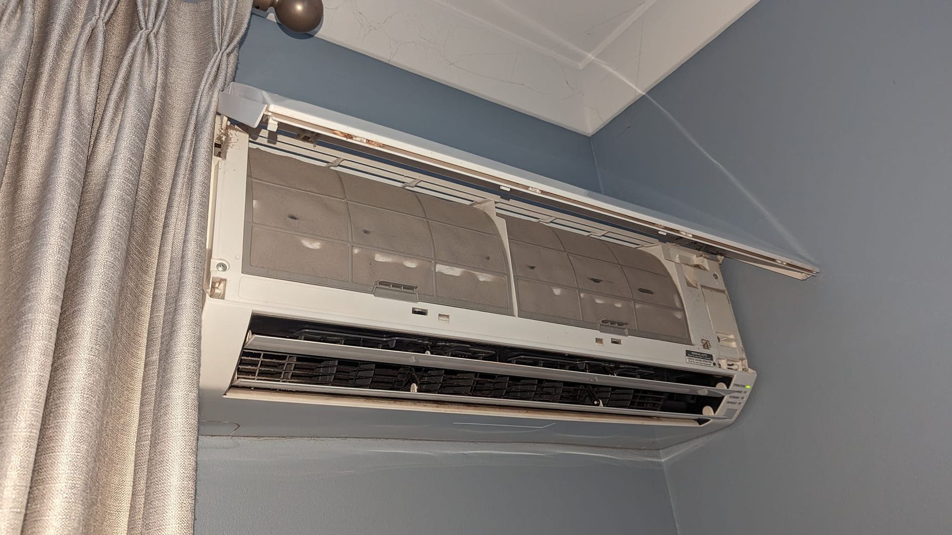 A White Air Conditioning Unit Mounted on a Blue Wall — Escarpment Air in Mount Saint Thomas, NSW