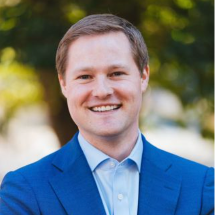 A man in a blue suit and white shirt is smiling for the camera.