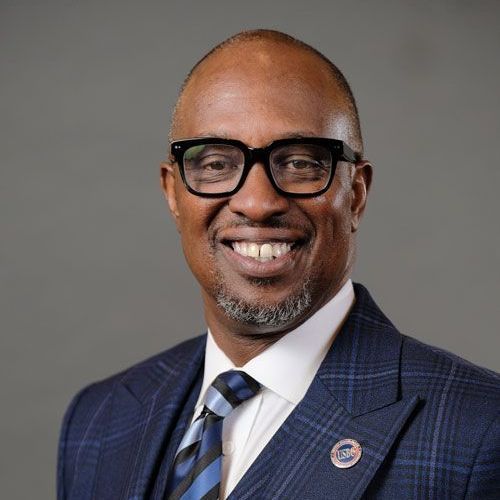 A man in a suit and tie is smiling for the camera.