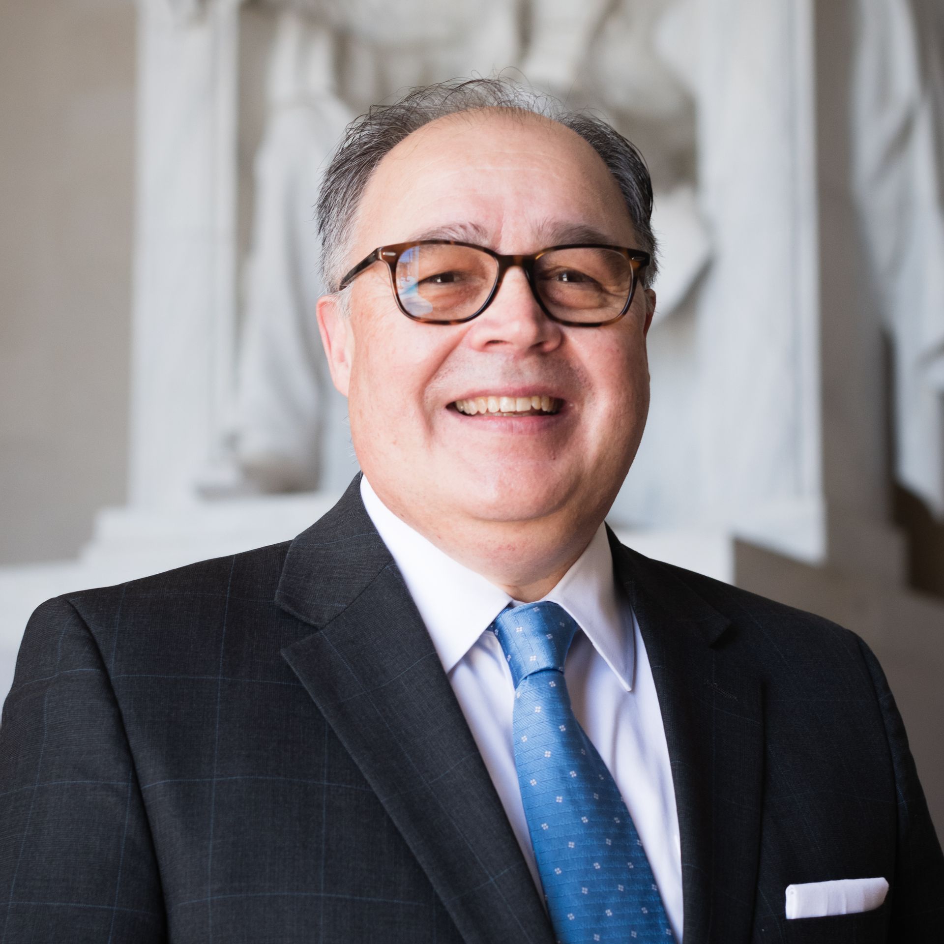 A man in a suit and tie is smiling for the camera