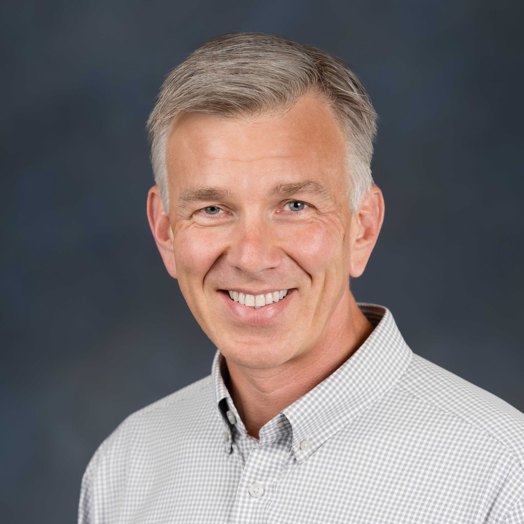 A man in a suit and white shirt is smiling for the camera