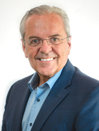 A man in a suit and glasses is smiling for the camera.