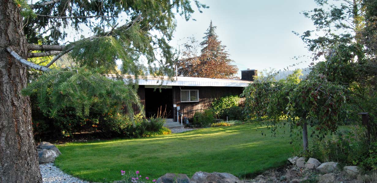 A house with a lush green lawn and trees in front of it.