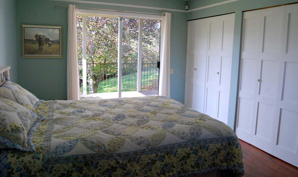 A bedroom with a large bed and a sliding glass door.