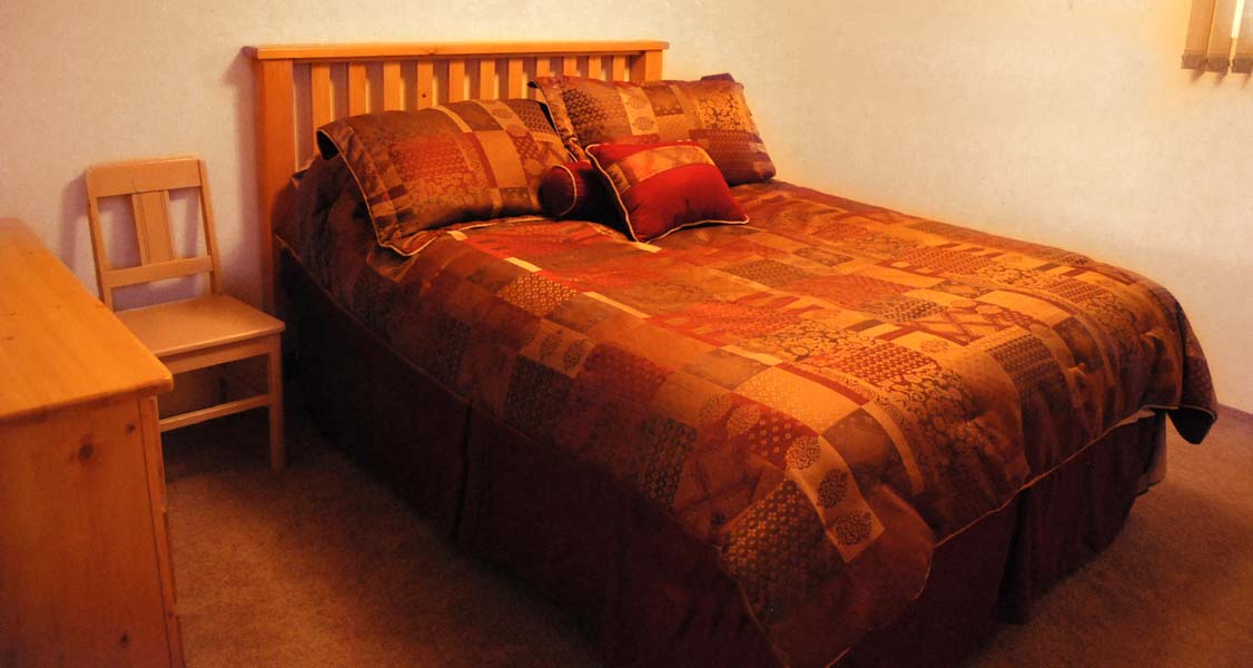 A bedroom with a bed , dresser and chair