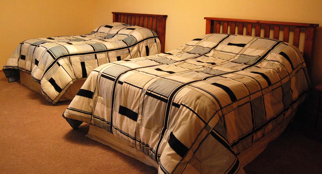 Two beds with plaid comforters in a bedroom