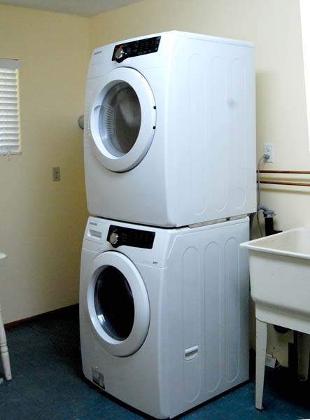 A washer and dryer are stacked on top of each other in a laundry room
