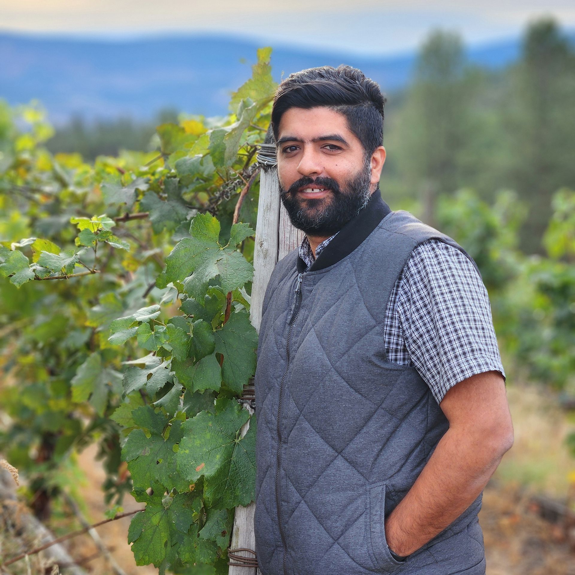 A man is sitting on a barrel holding a bottle of wine.