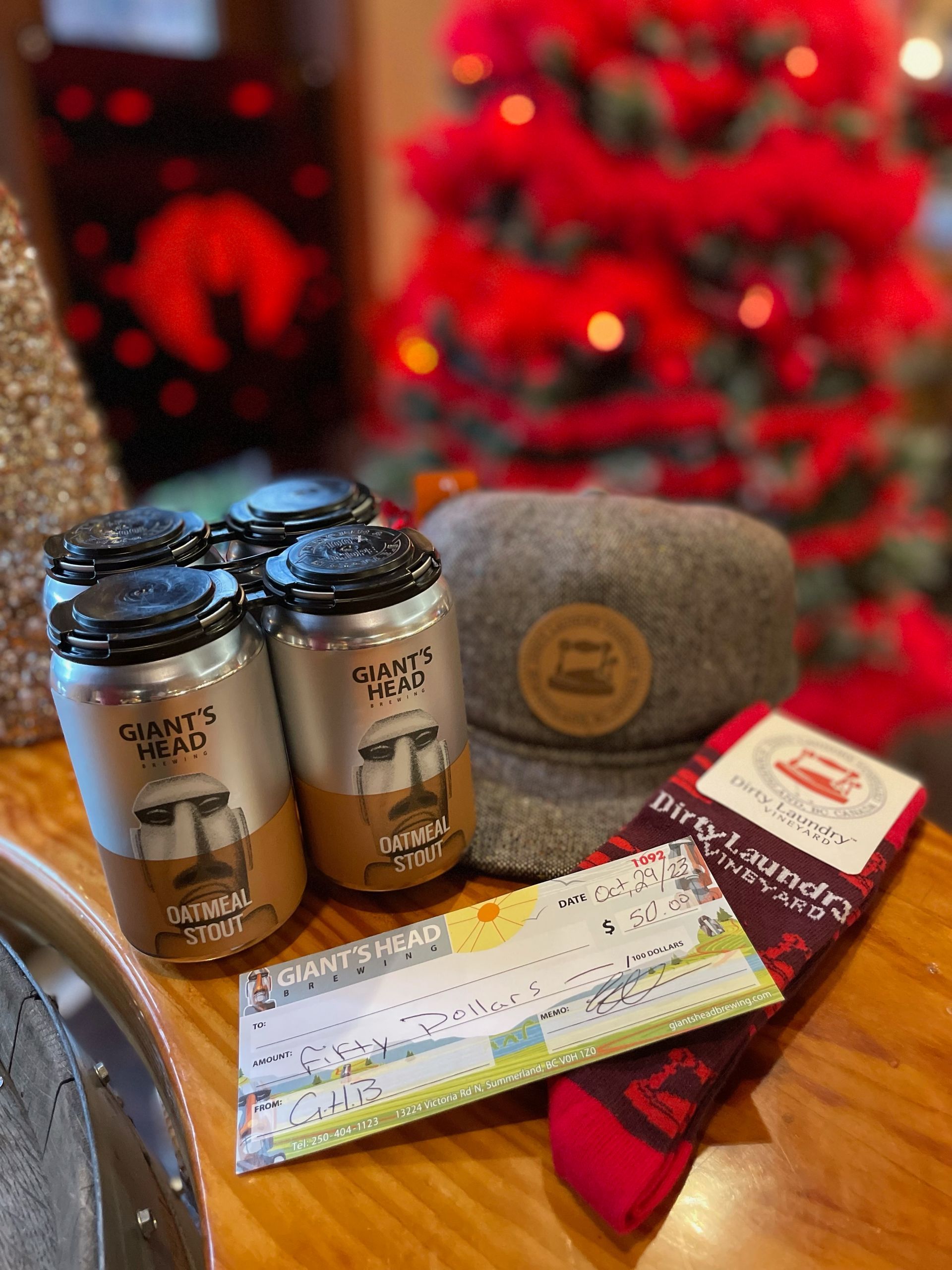 A christmas tree is behind a table with a hat , socks , and cans of beer.