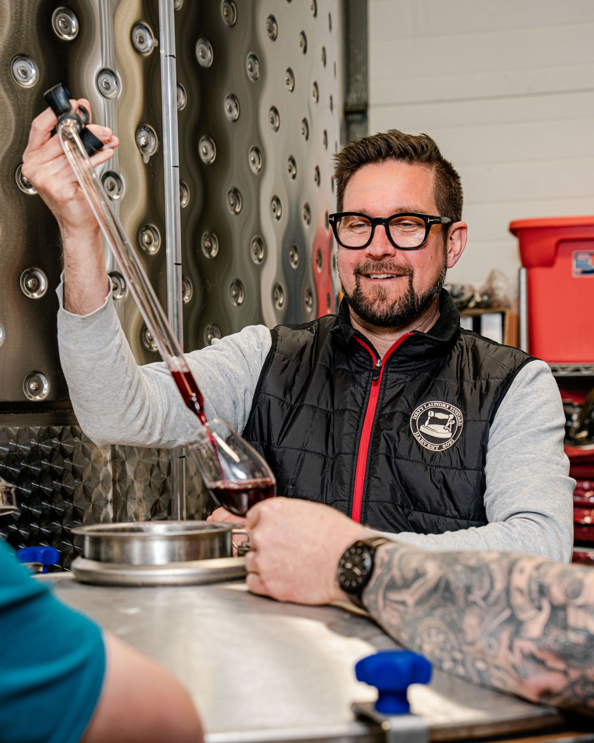 A man with glasses is pouring wine into a glass