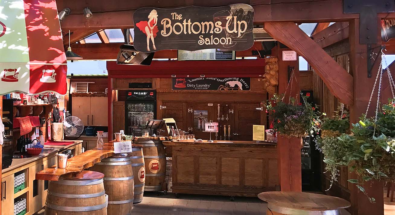 A restaurant with barrels and a sign that says bottoms up saloon.