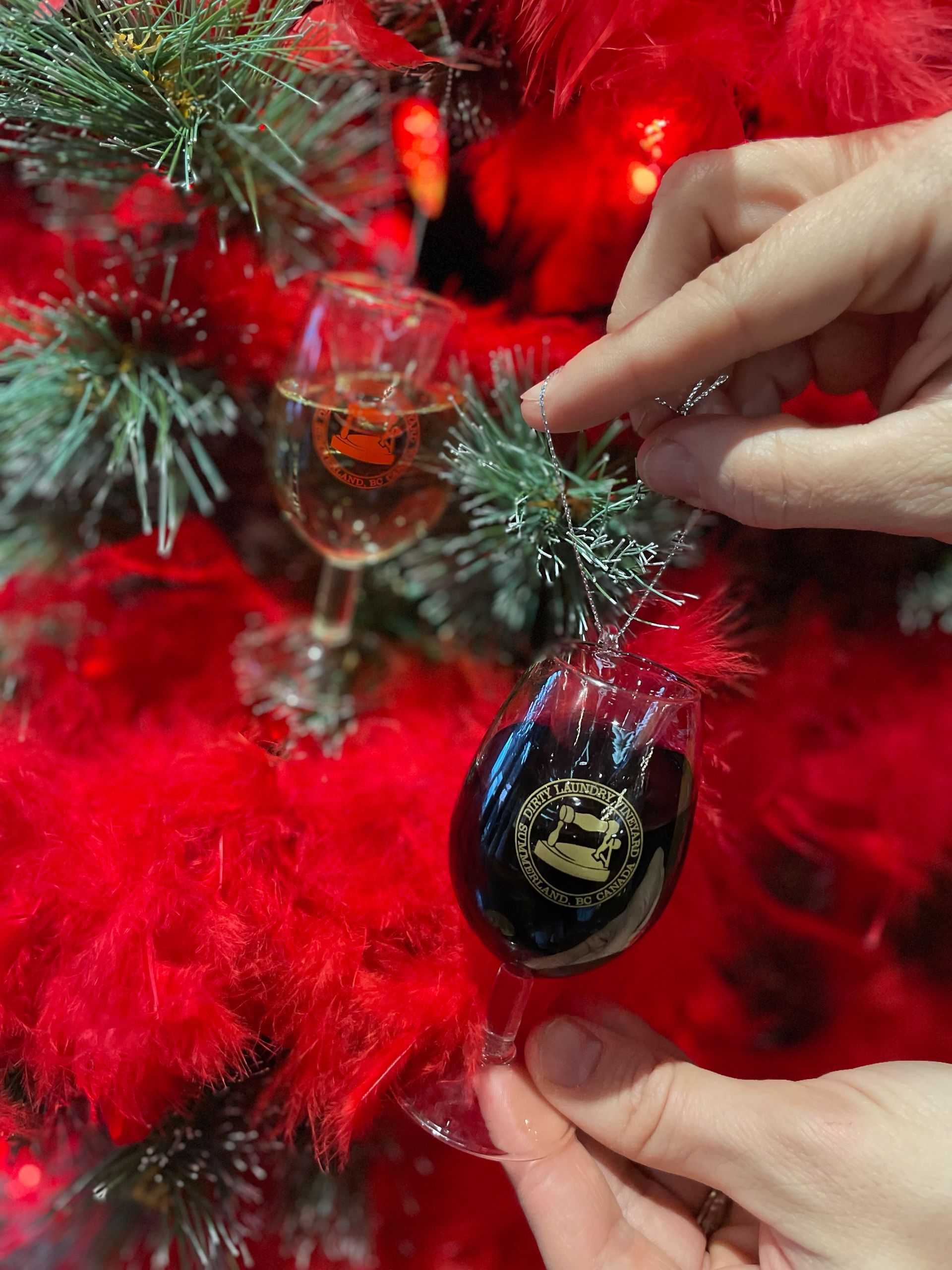 A person is holding a christmas ornament in front of a christmas tree.