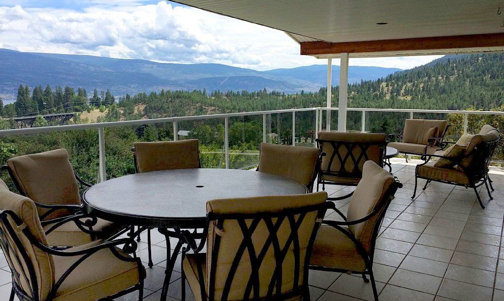 A table and chairs on a balcony with mountains in the background