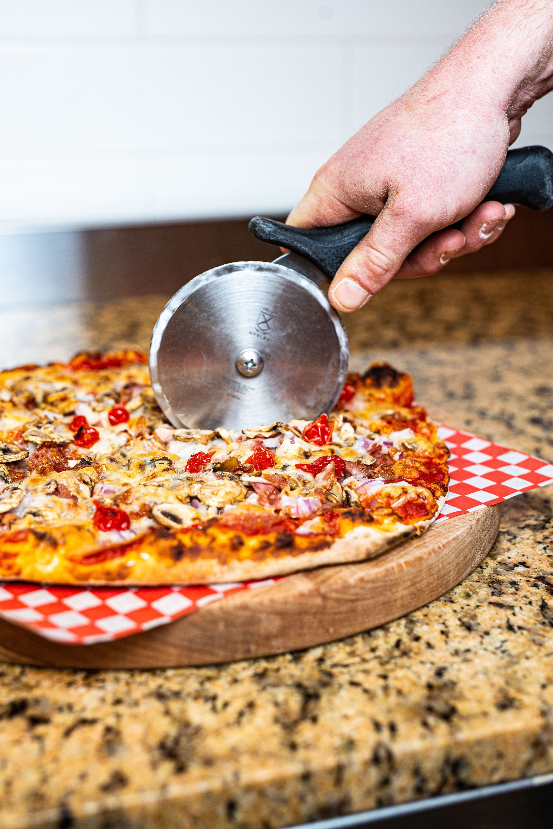 A person is cutting a pizza with a pizza cutter.