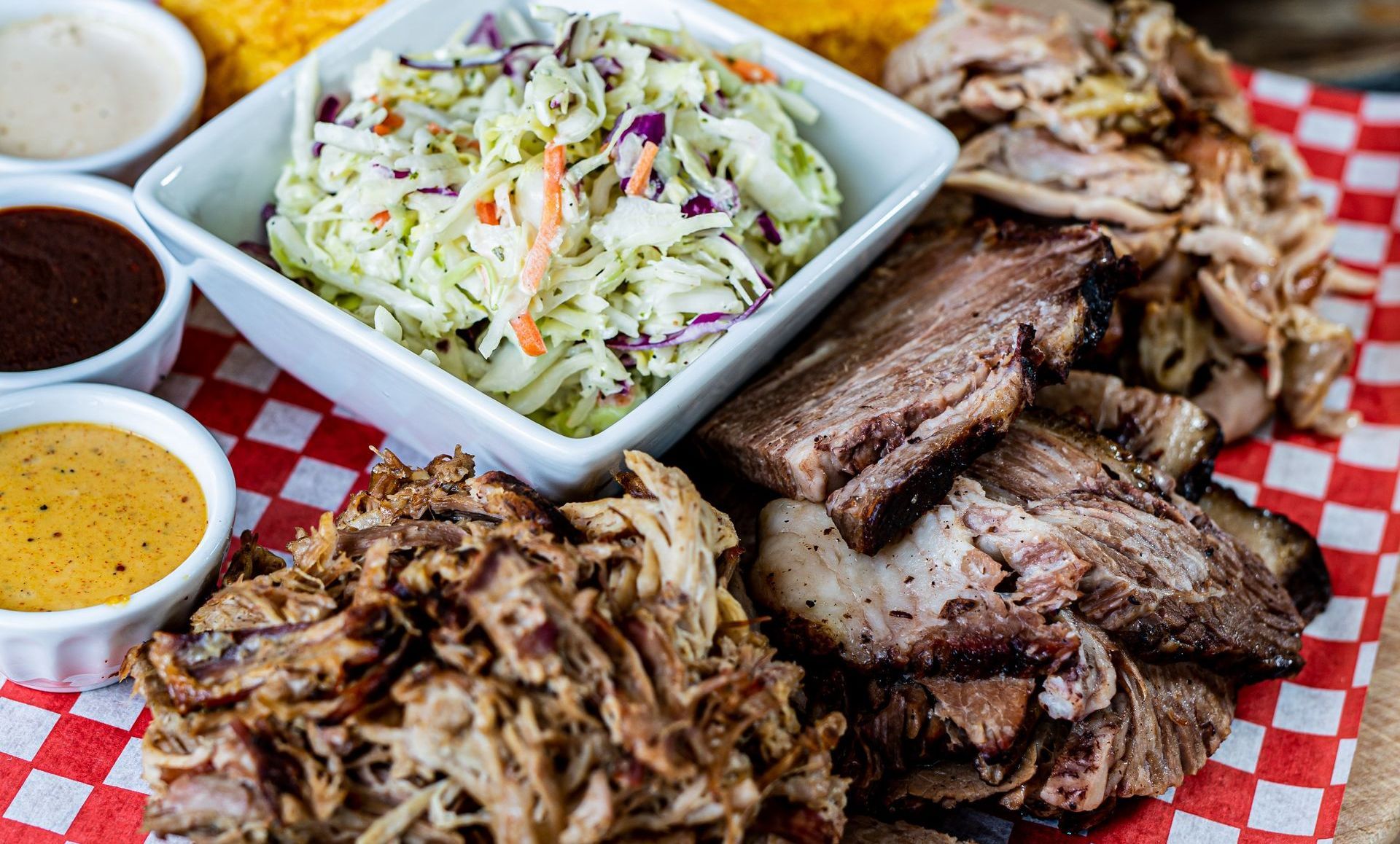 There is a plate of meat and a bowl of coleslaw on the table.