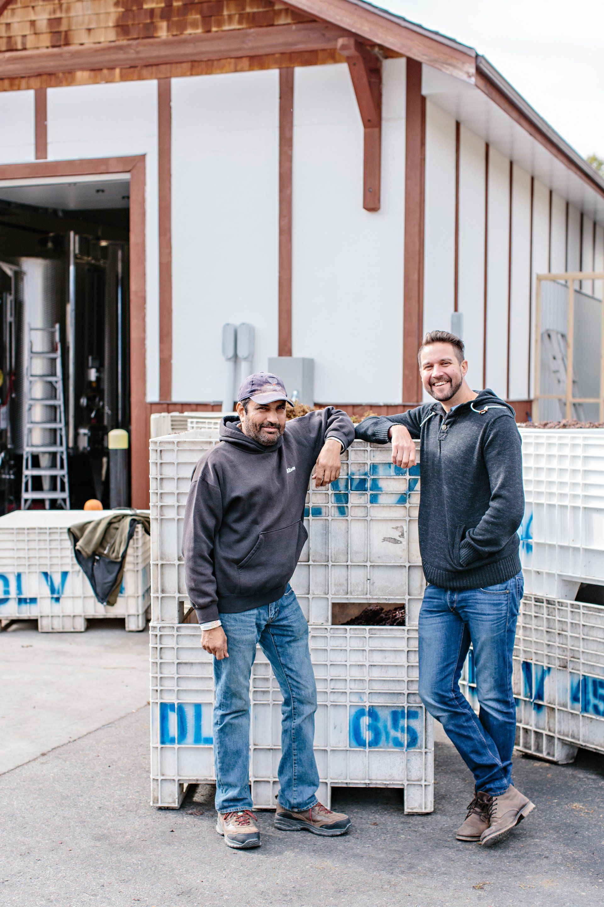 Two men are standing next to each other in front of a building.
