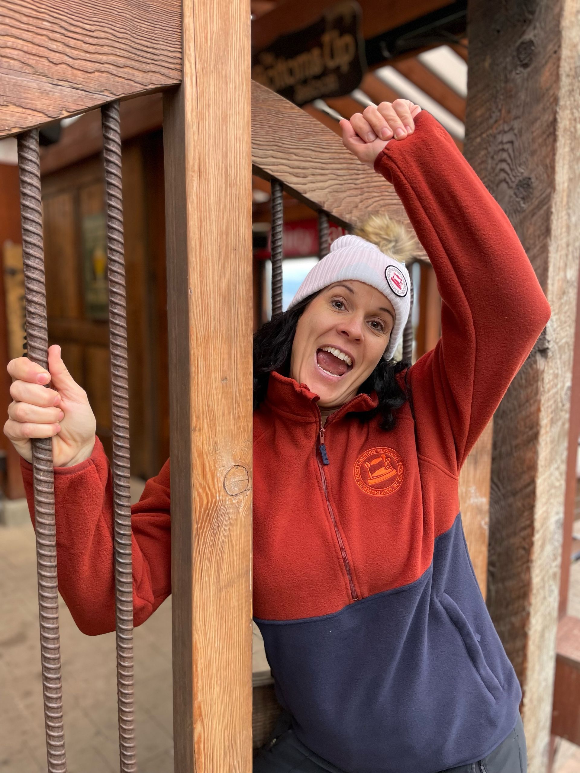 A woman in a red and blue sweater is standing next to a wooden pole.