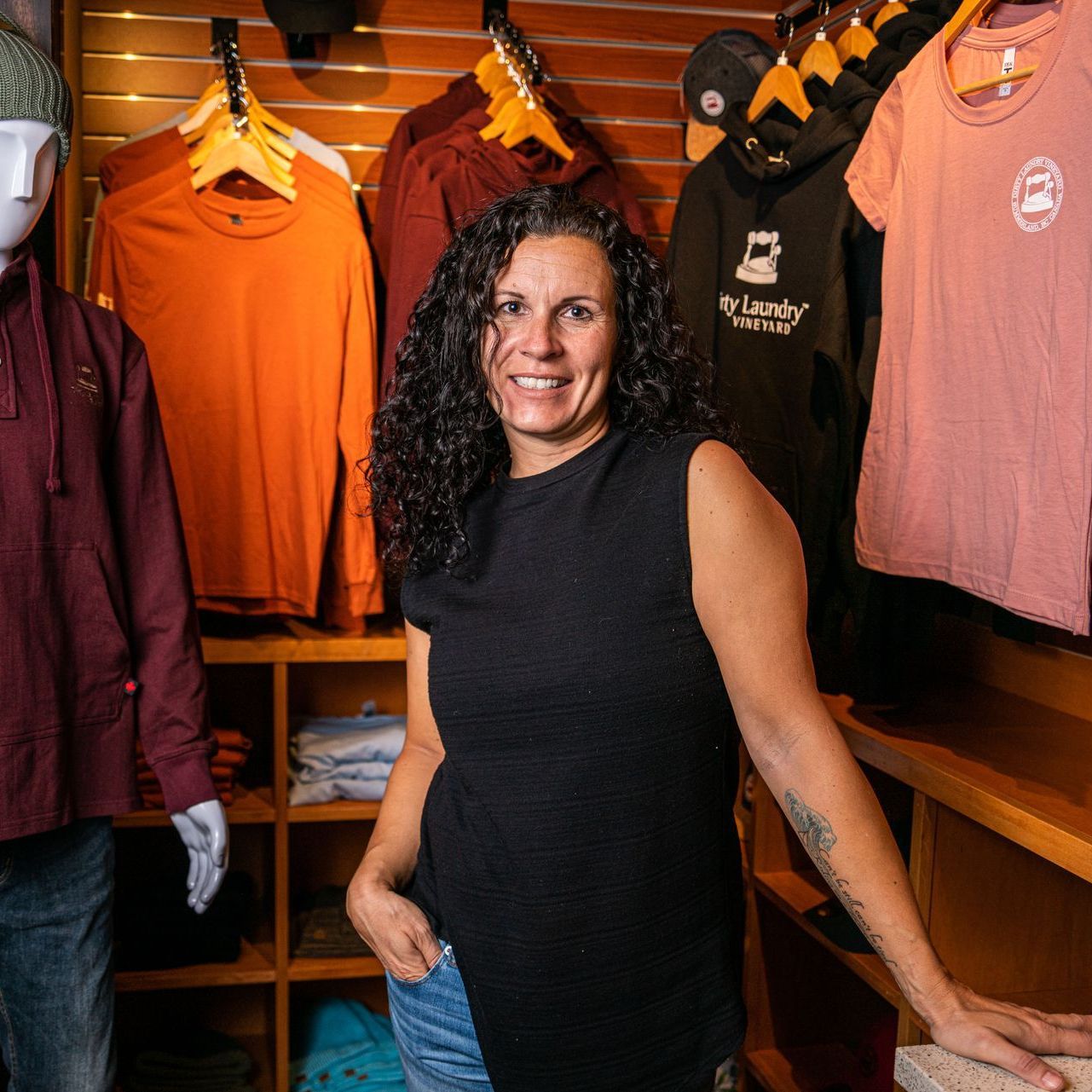 A woman is standing in front of a mannequin in a clothing store.