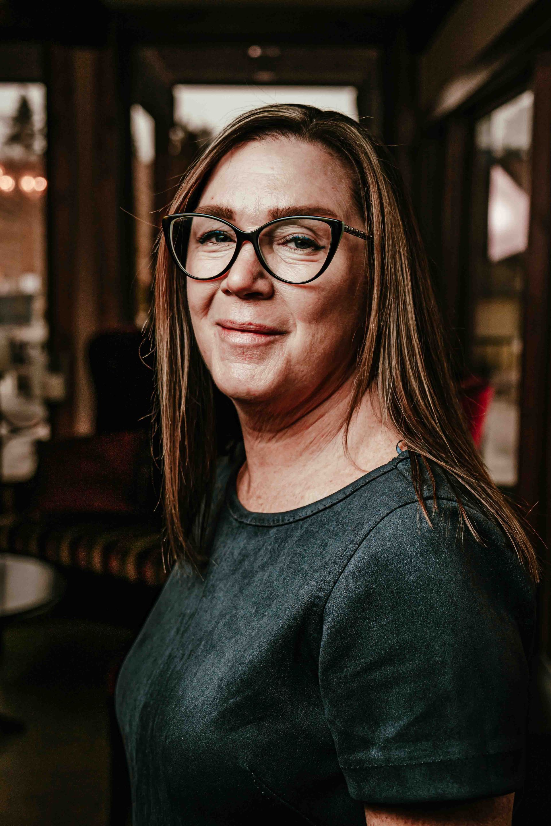 A woman is holding a glass of wine in a wine cellar.