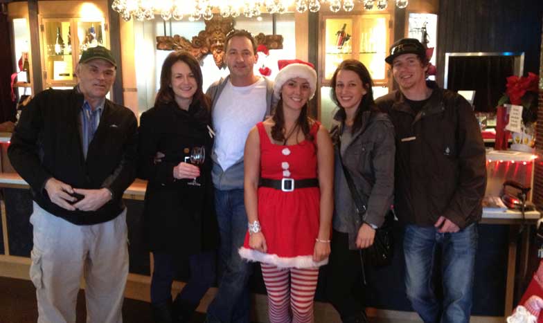 A group of people posing for a picture including a woman in a santa outfit