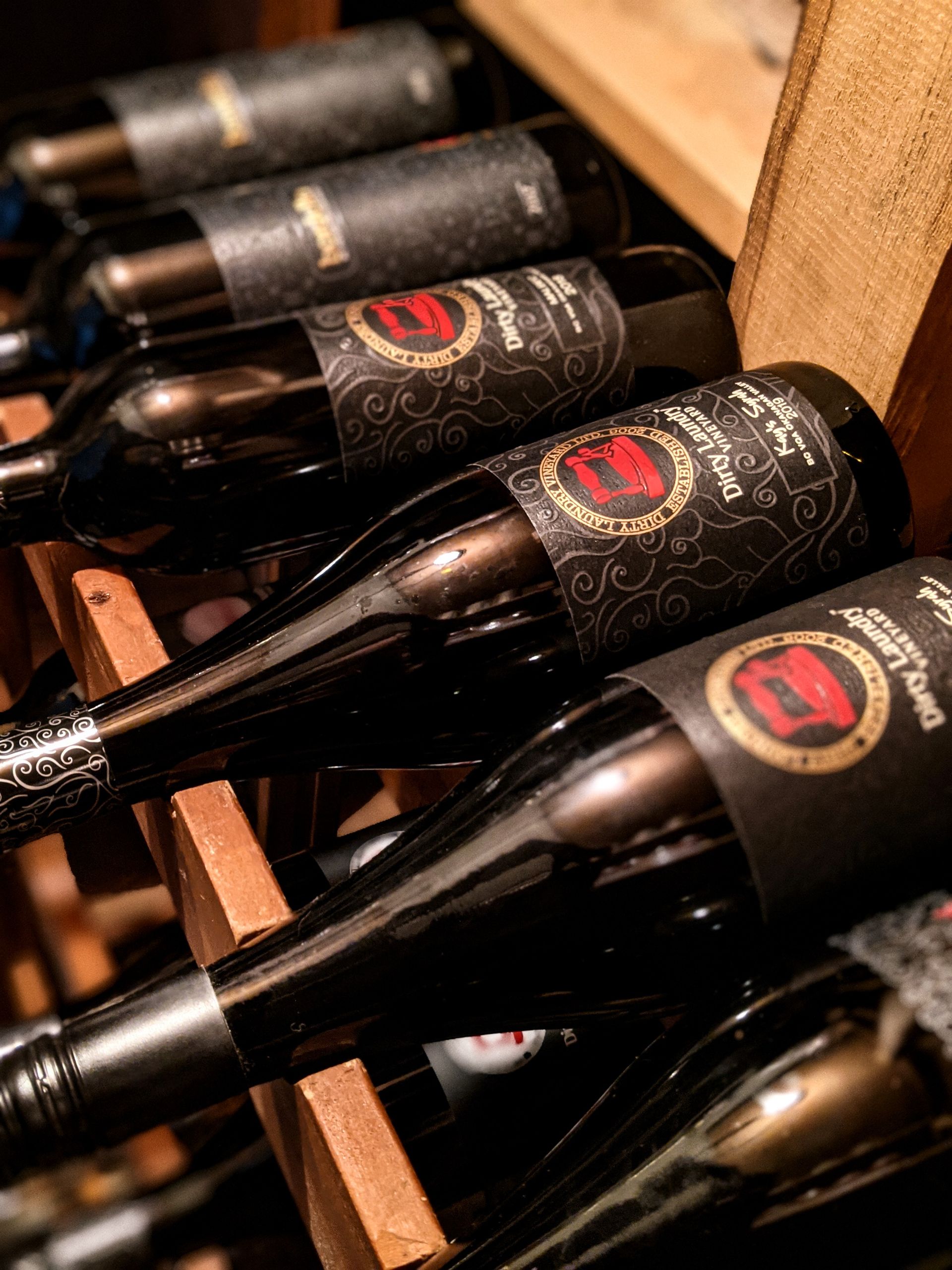 A row of wine bottles sitting on top of each other on a wooden rack.