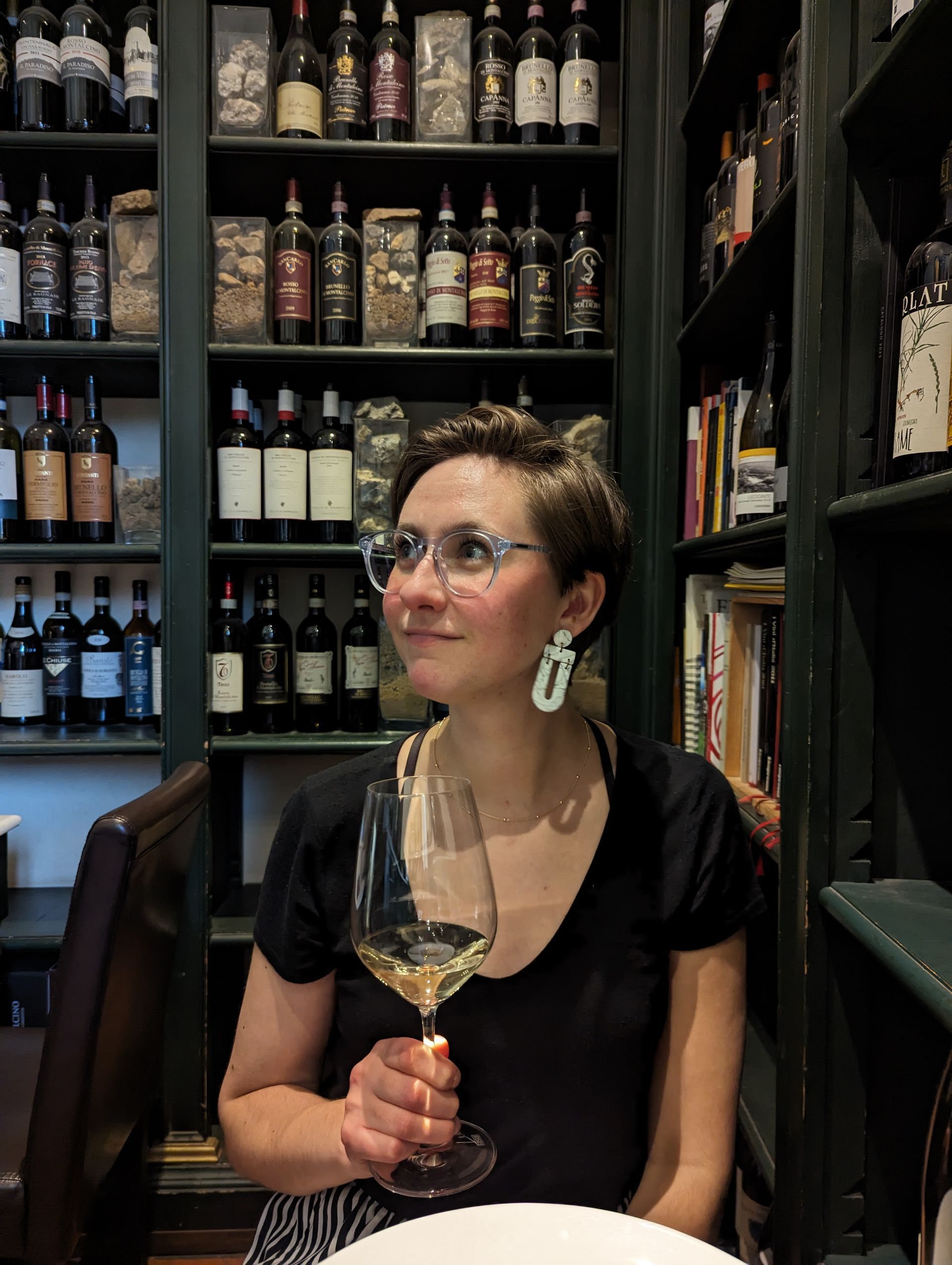 A woman is sitting at a table holding a glass of wine.