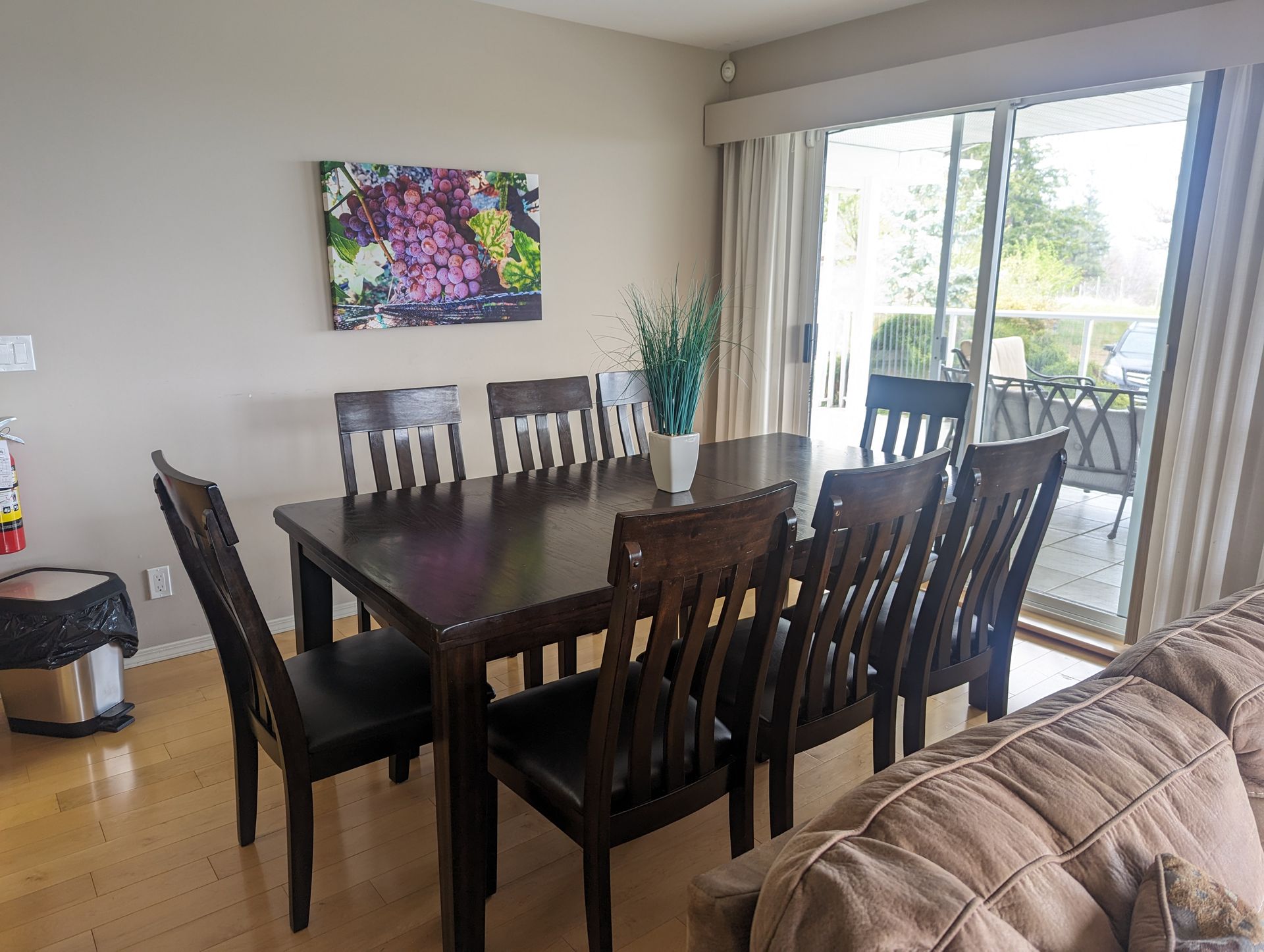 A dining room table and chairs in a living room with a sliding glass door.