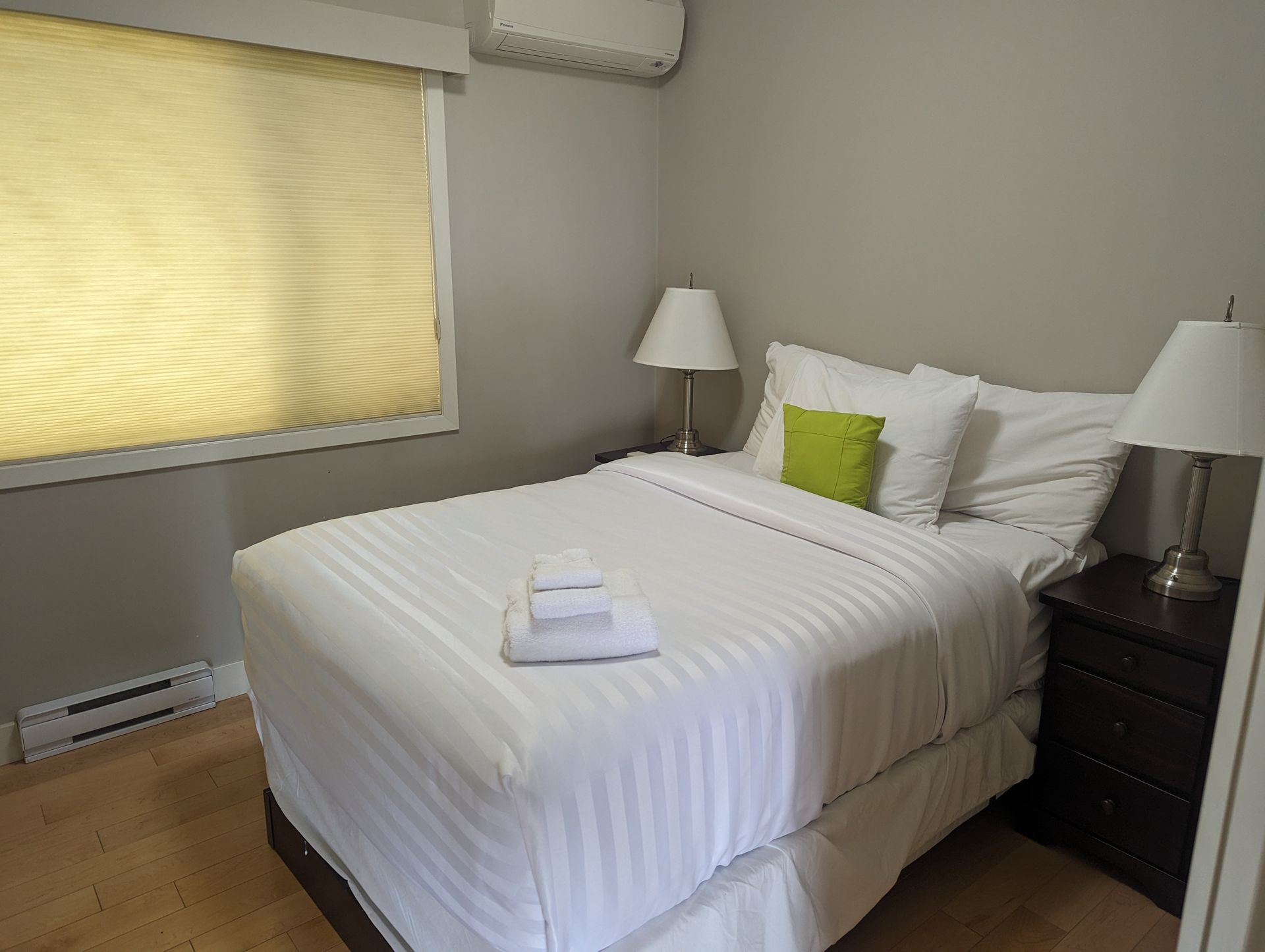 A bedroom with a bed , nightstand , lamps and a window.