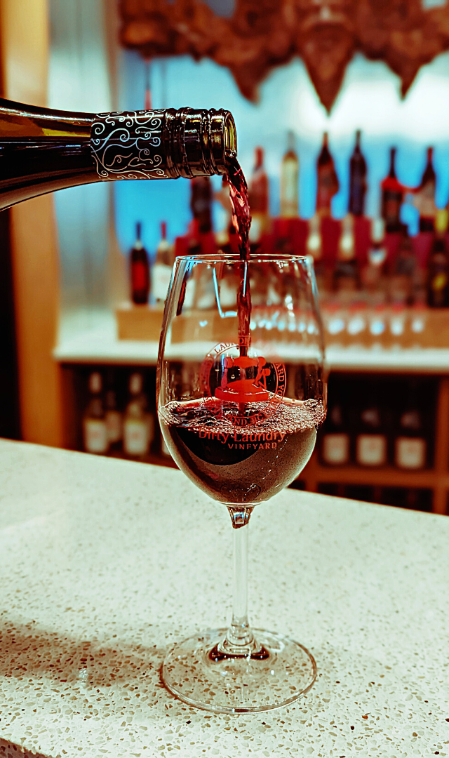 A glass of red wine is being poured from a bottle.