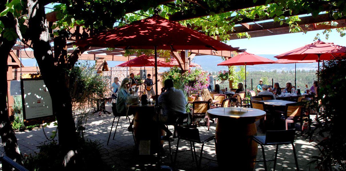 A group of people are sitting at tables under red umbrellas.