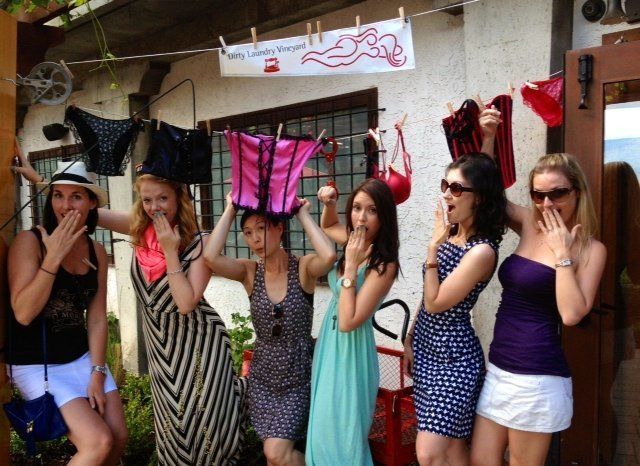 A group of women are posing for a picture with clothes hanging on a clothes line