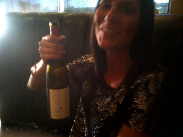 A woman is holding a bottle of wine in her hand