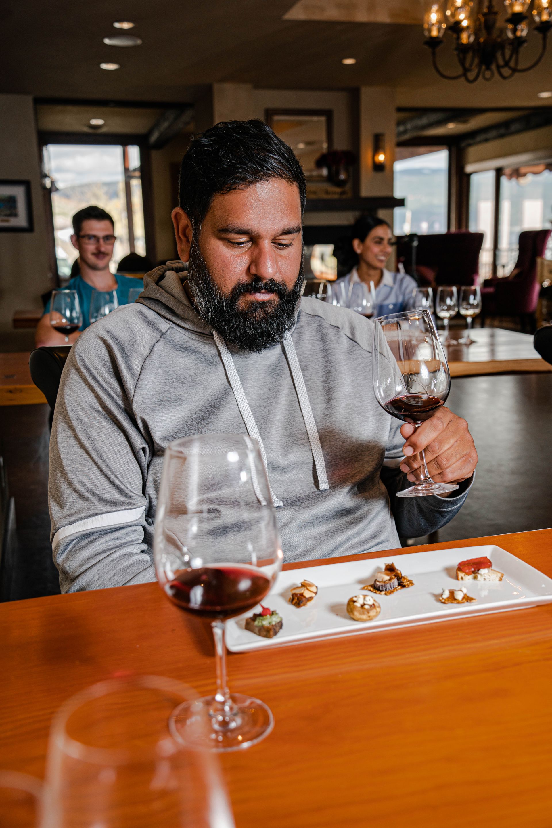 A man is sitting at a table with a glass of wine and a plate of food.