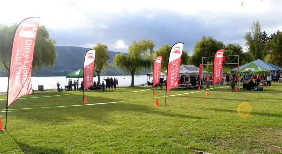 A group of people are standing in a grassy field next to a lake.