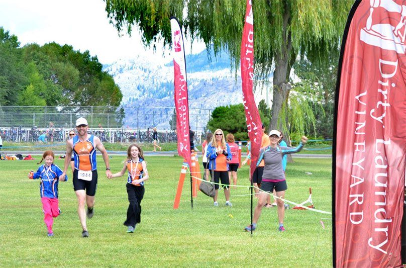 A group of people running in a field with a banner that says dry country vineyard