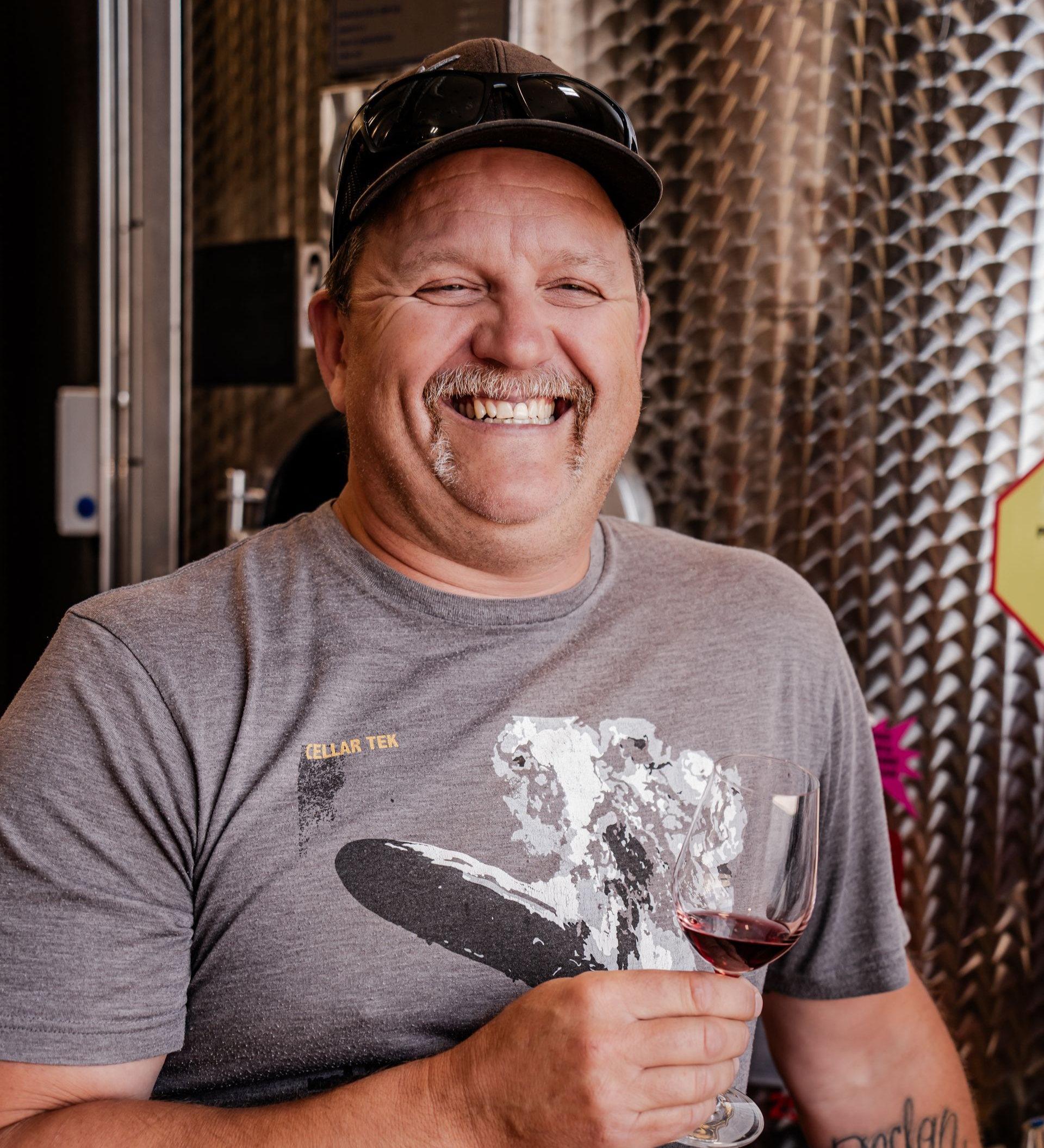 A man leaning on a counter holding a glass of wine