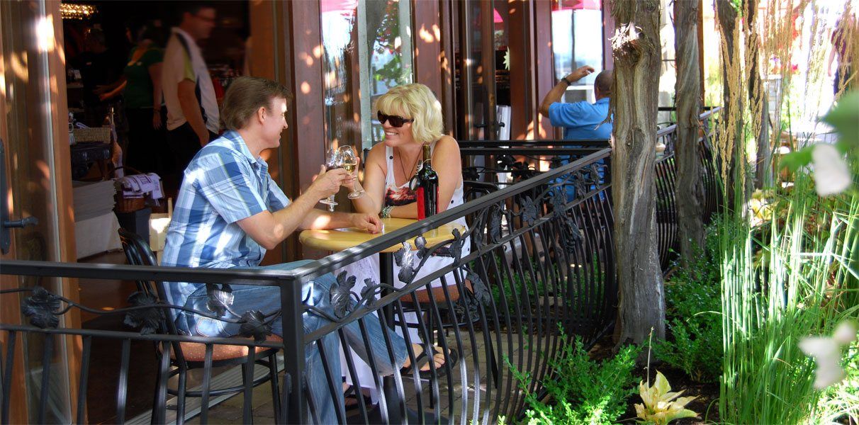 A man and a woman are sitting at a table outside of a restaurant.