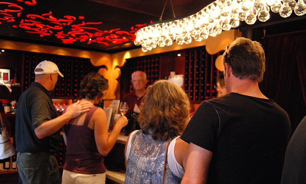 A group of people are standing around a bar talking to each other