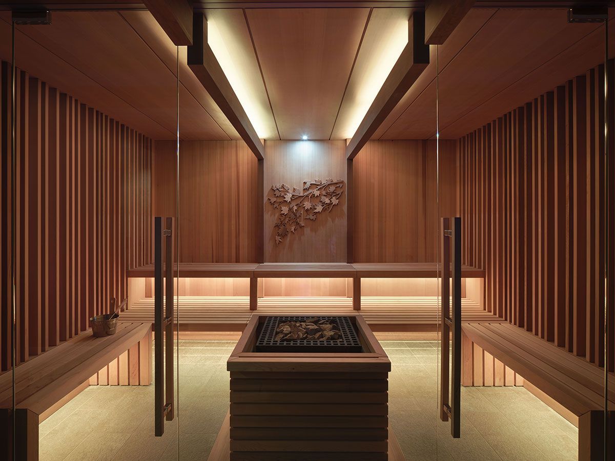 A wooden sauna with a glass door and benches