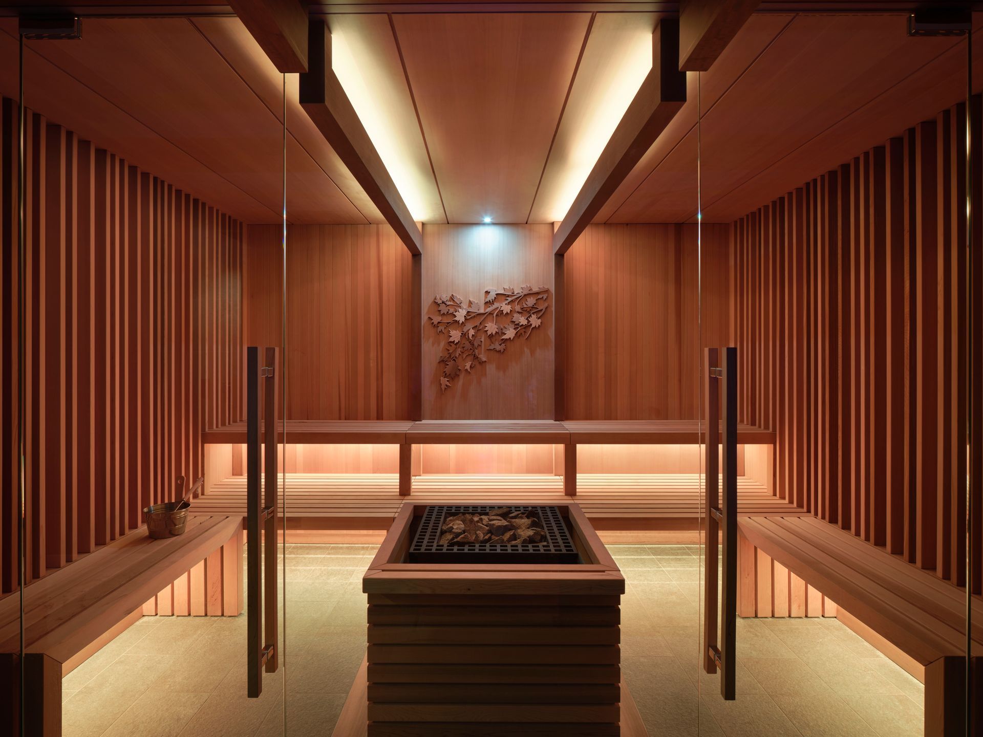 A wooden sauna with a glass door and benches