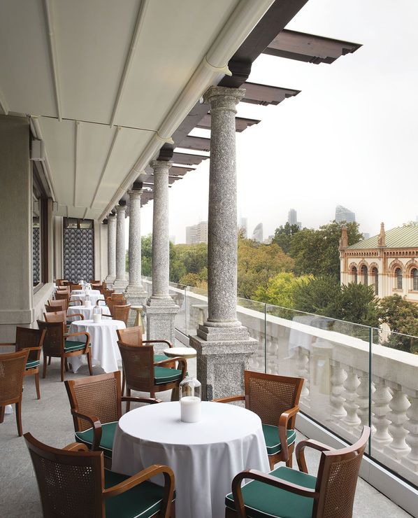 A balcony with tables and chairs and a view of the city
