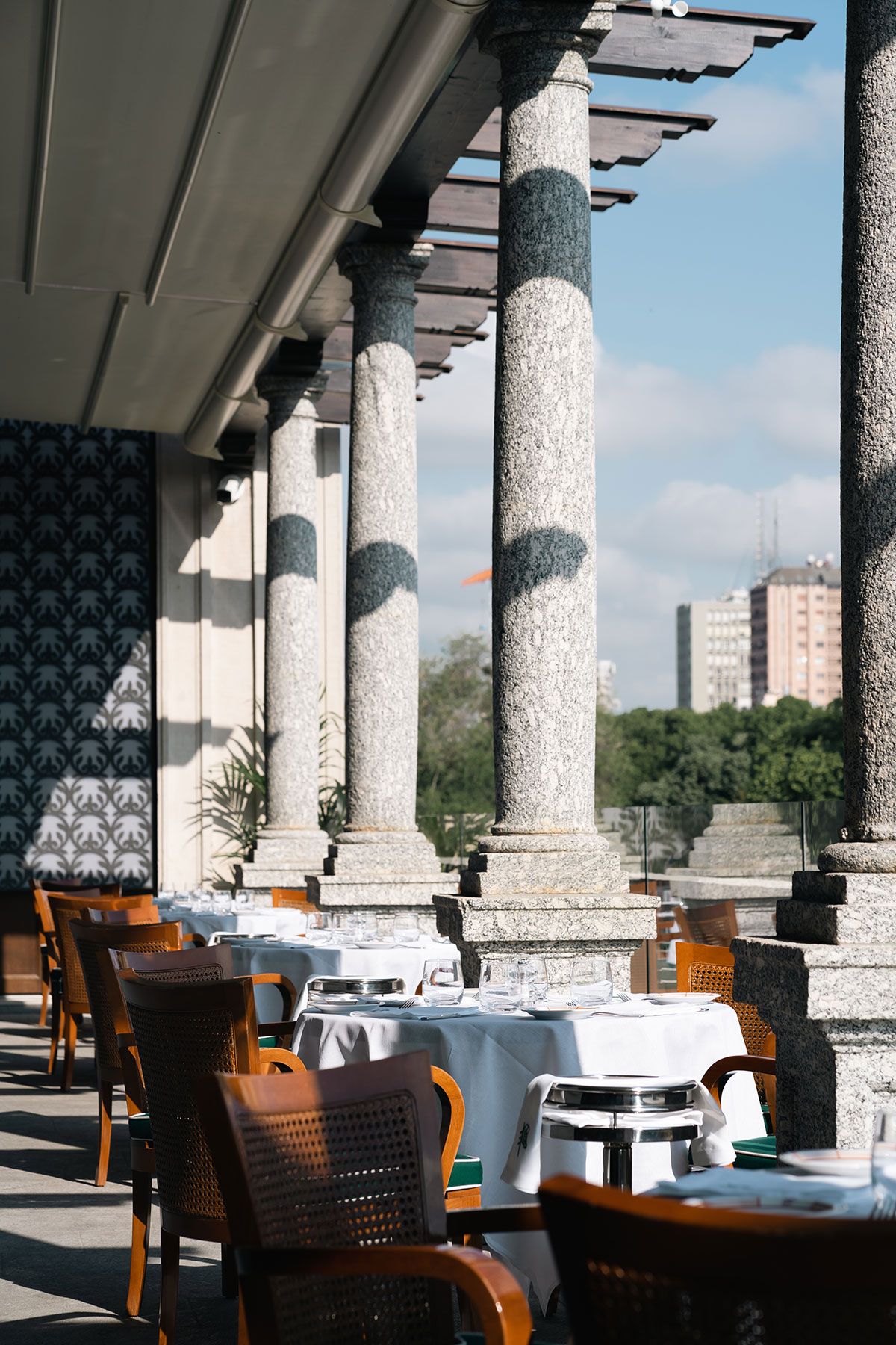 A restaurant with tables and chairs and columns in the background