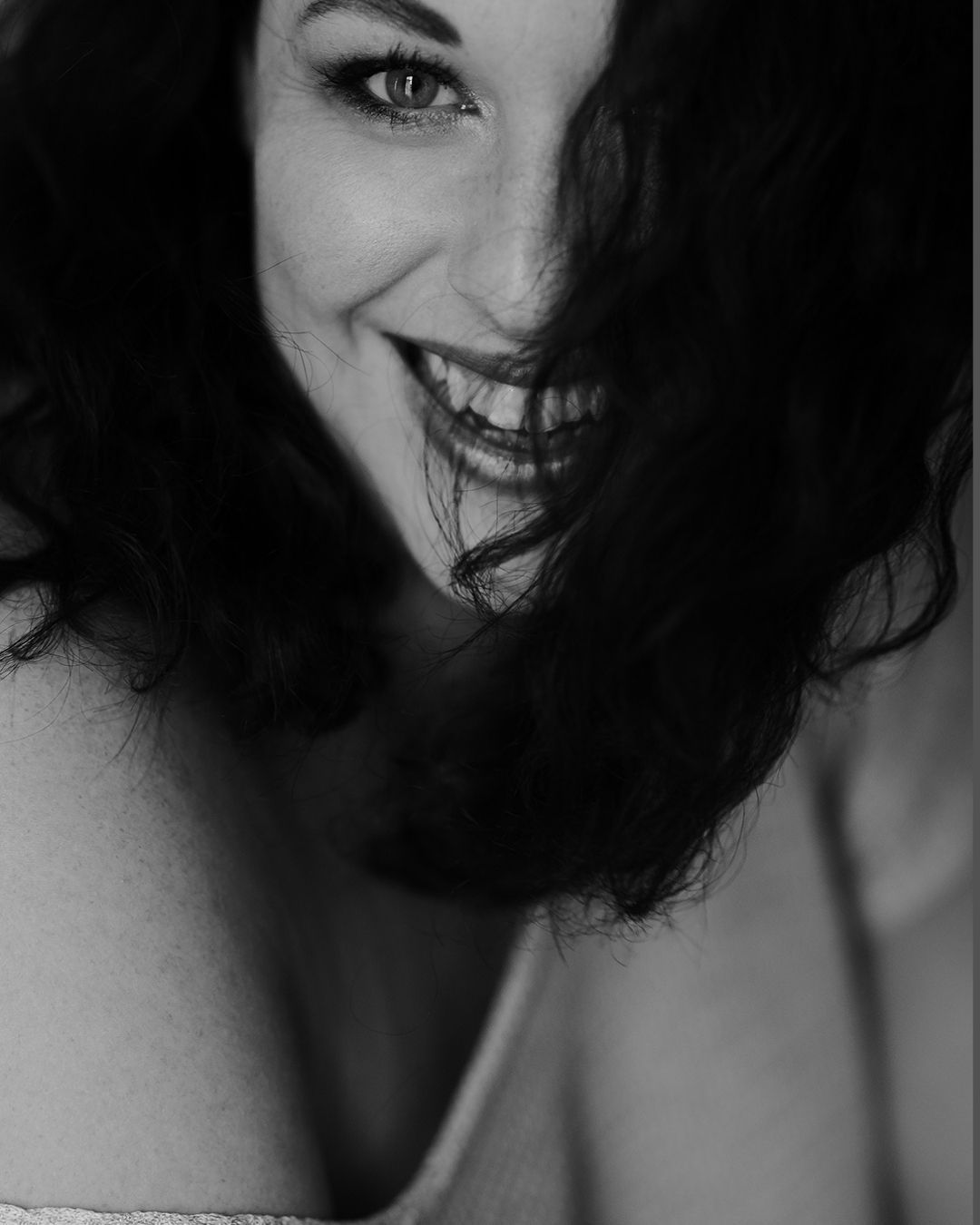 Ein Schwarzweissfoto einer lächelnden Frau, deren Haare im Wind wehen.