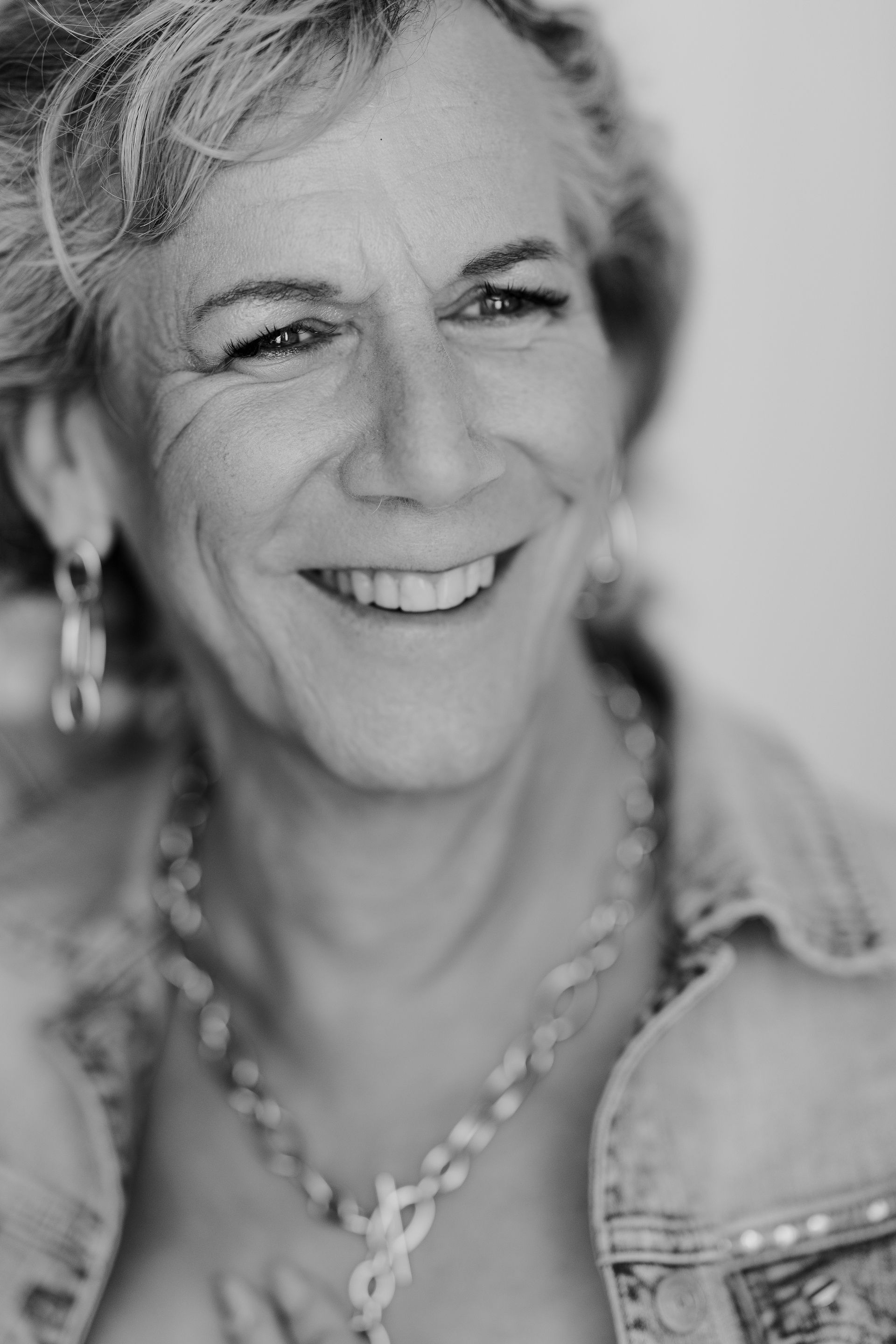 Ein Schwarzweissfoto einer lächelnden Frau, die eine Halskette trägt.