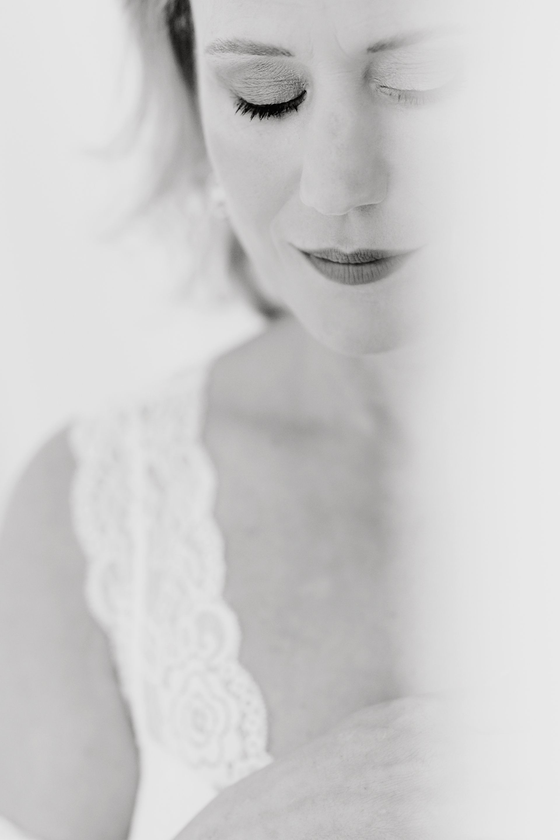 Ein Schwarzweissfoto einer Frau in einem weissen Kleid mit geschlossenen Augen.