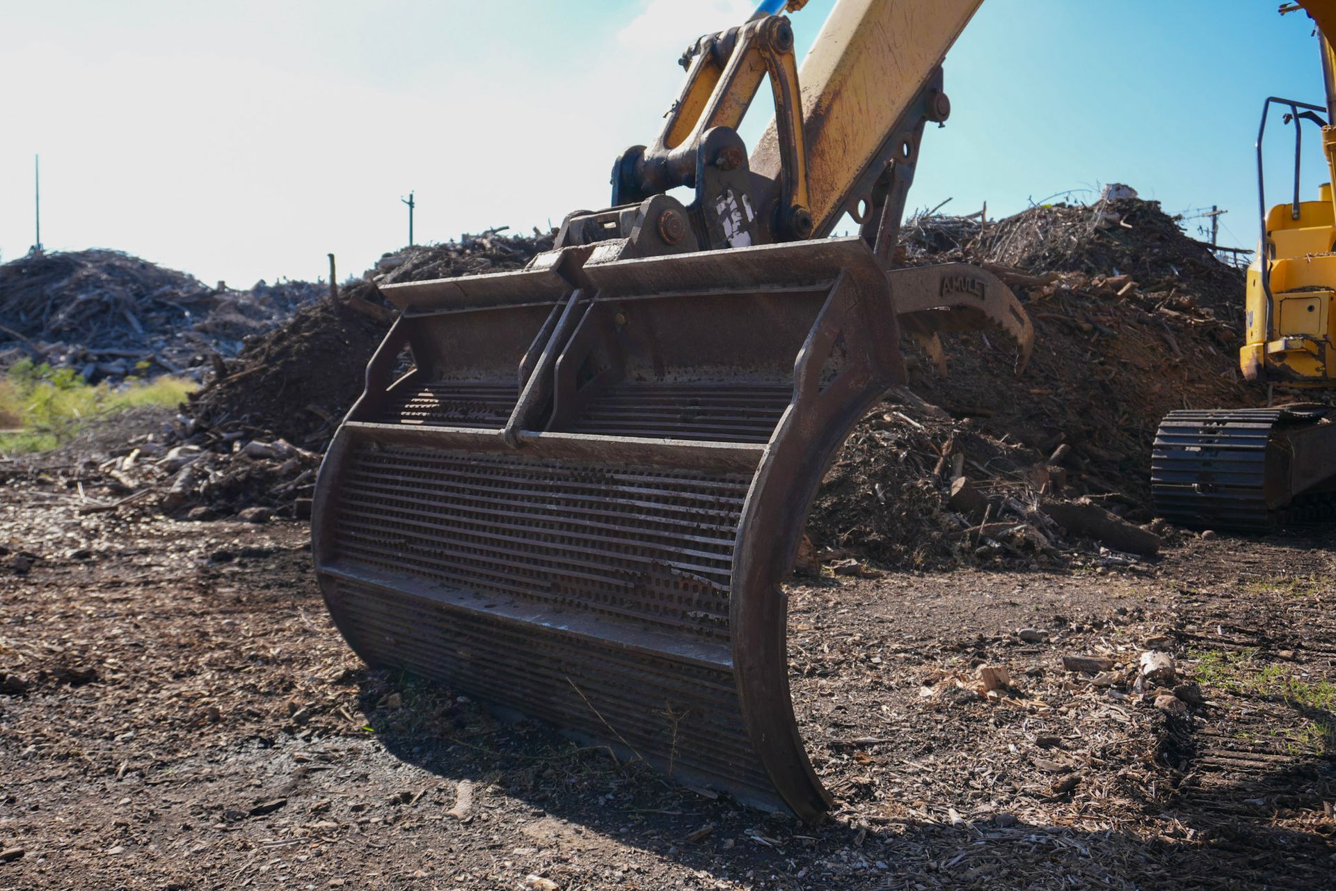 Yellow front-end loader on a construction site with a hilly, dry landscape in the background.