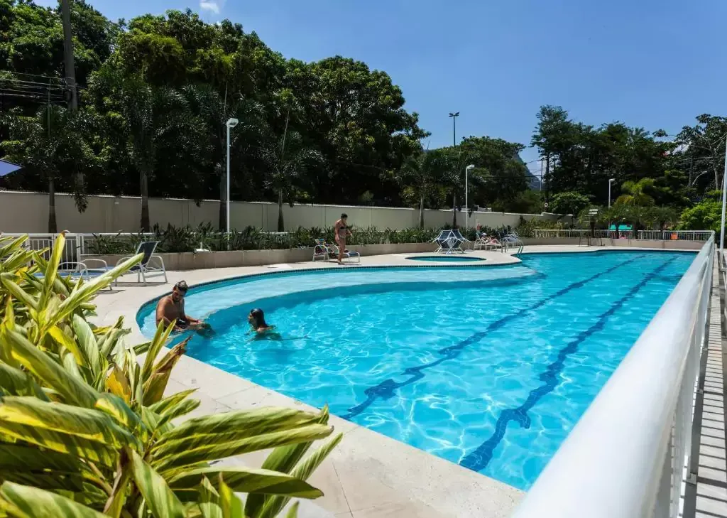 Uma grande piscina com uma banheira de hidromassagem no meio - Best in Rio Stay Convention Suítes